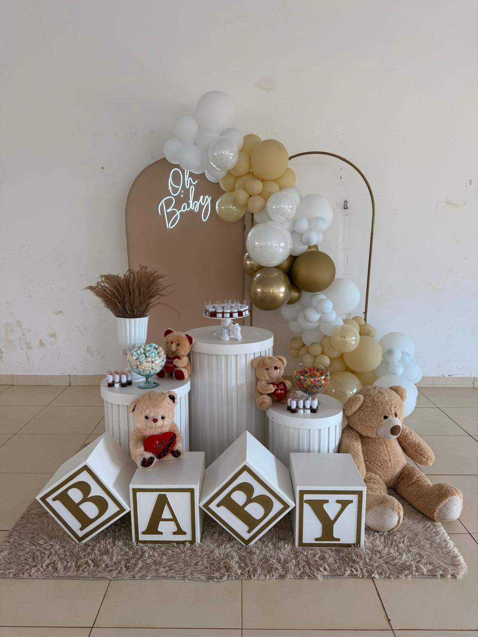 Chá de bebê com painel arco nude, neon Oh Baby, cubos BABY dourados, ursinhos de pelúcia e arco de balões branco, marfim e dourado