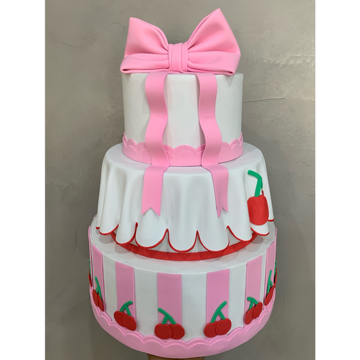 Bolo de três andares decorado em rosa e branco sobre suporte de mesa de festa