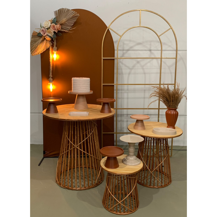 Trio de mesas de madeira com base ripada, painel arco terracota e arco dourado para decoração de festas