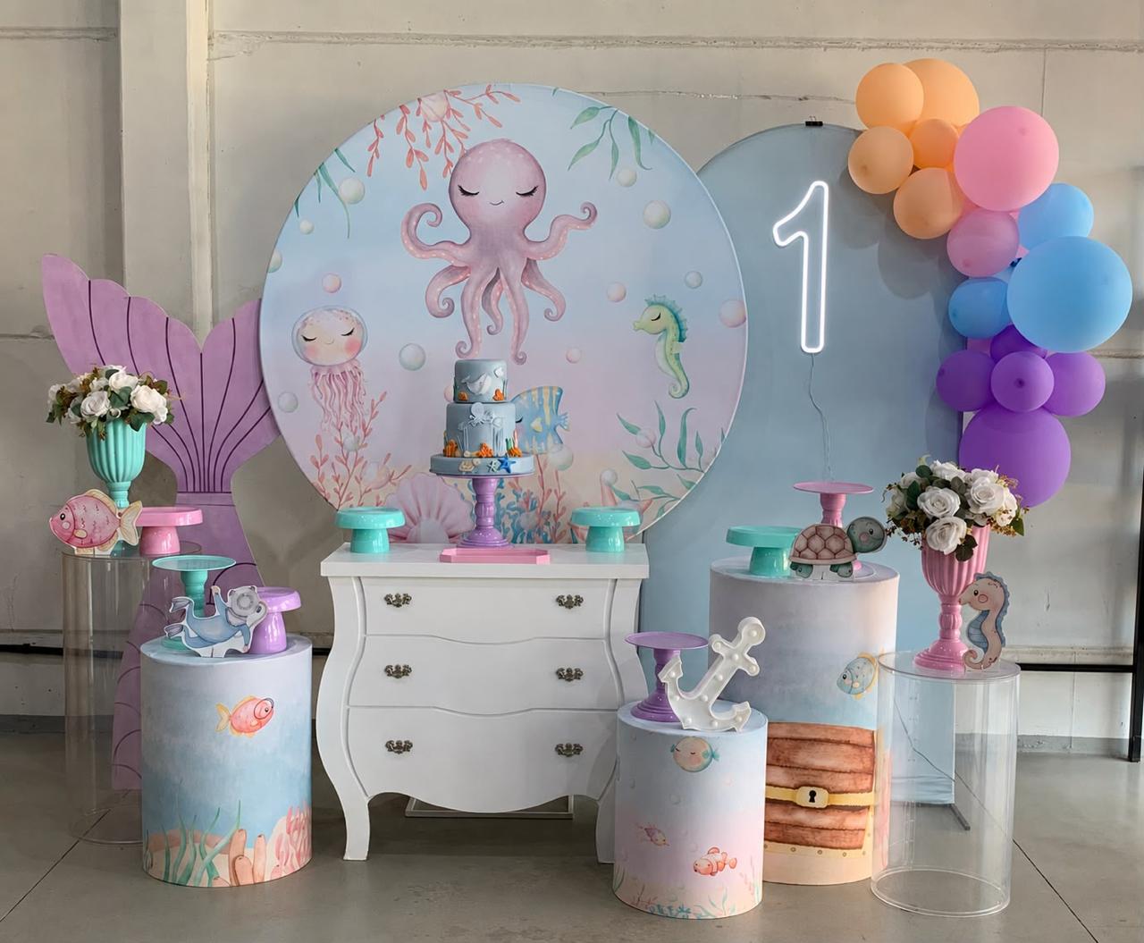 Decoração de 1 ano tema fundo do mar com painel de polvo, neon número 1, cômoda provençal e cilindros ilustrados