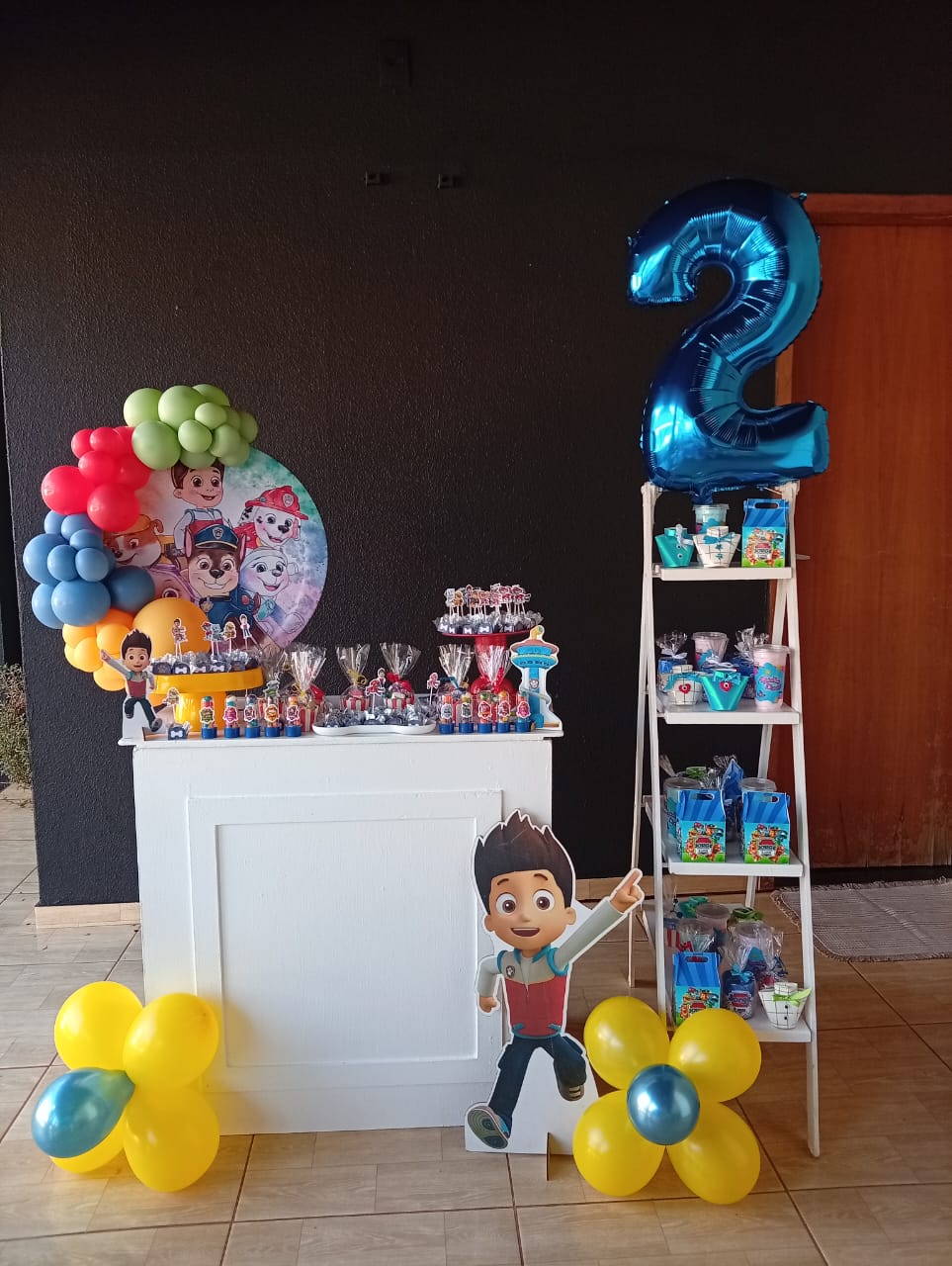 Kit montado no tema Patrulha Canina, com mesa de doces, balões coloridos, personagens Ryder e cachorros, e número 2 azul metalizado — decoração infantil