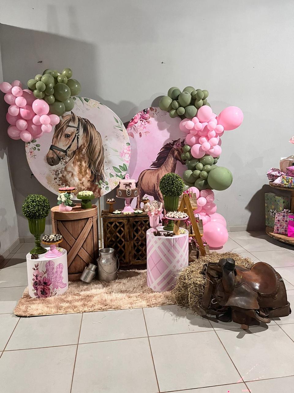 Decoração infantil tema cavalos com painéis redondos florais, arcos de balões rosa e verde oliva, fardo de feno e sela