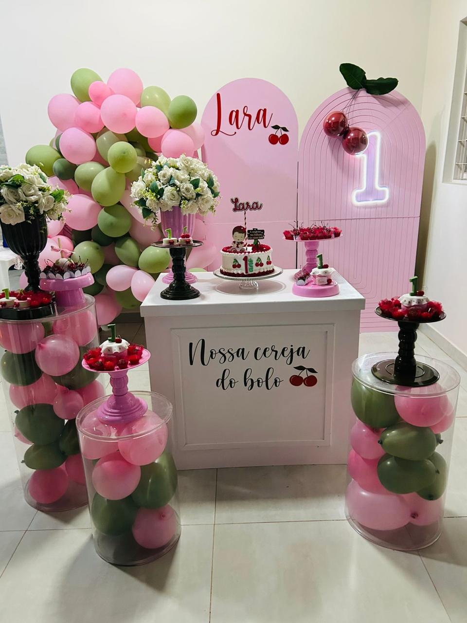 Festa de 1 ano tema cereja com painéis arco rosa, neon número 1, cilindros de acrílico com balões rosa e verde