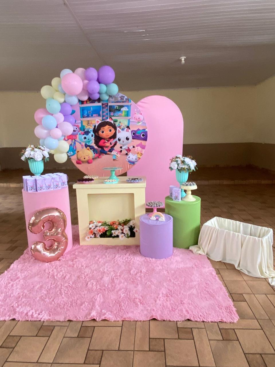 Festa de 3 anos tema Gabby's Dollhouse com painel redondo, balão número 3 rosé, cilindros coloridos e arco de balões pastel